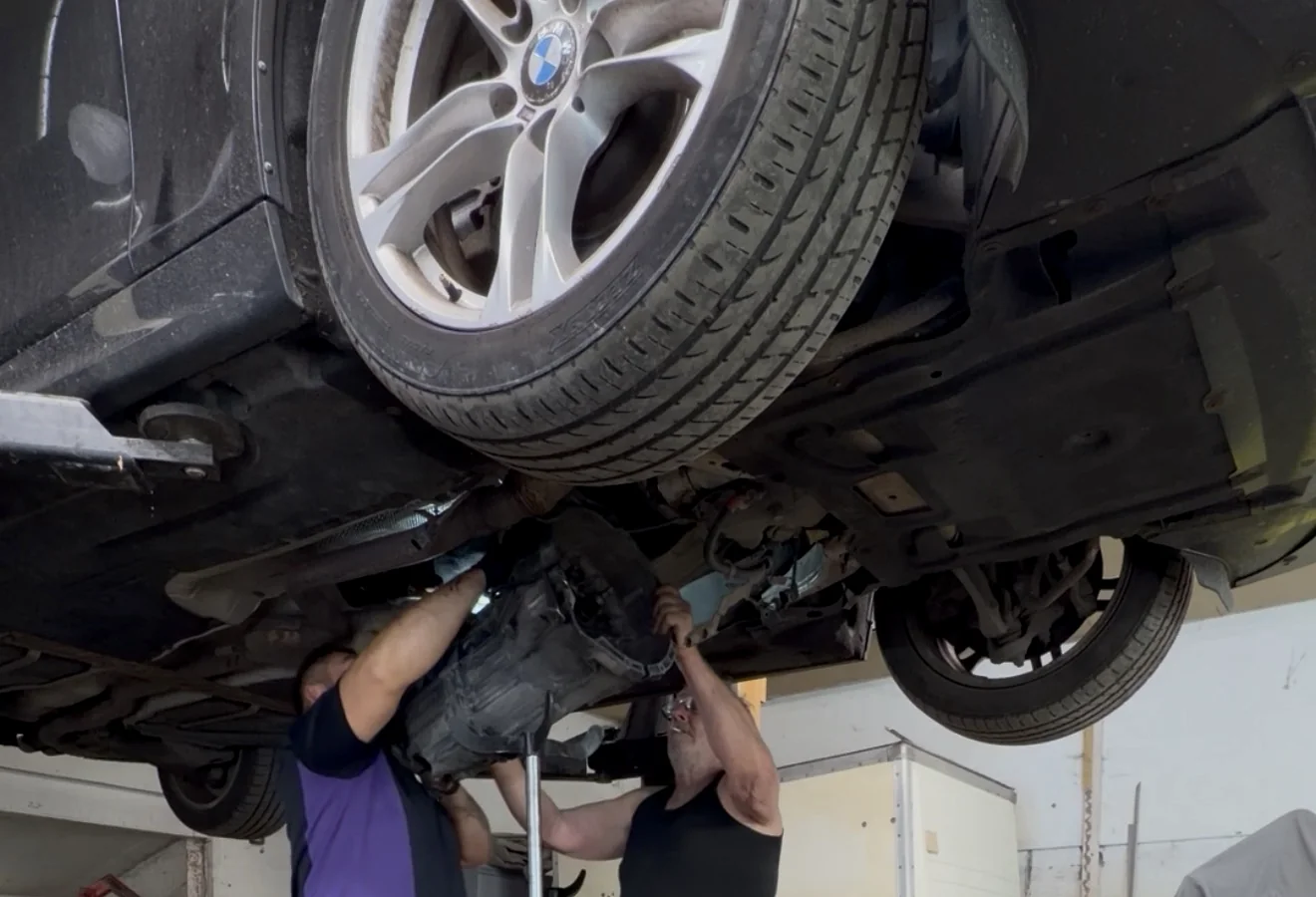 Gearbox removal work beneath a BMW